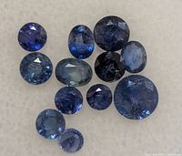 Twelve round blue sapphires arranged on white background