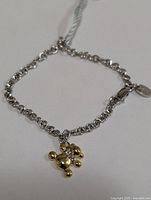 Full view of silver rolo-link bracelet with gold-tone diamond charm