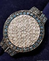 Top view of ring showing round cluster of white diamonds and surrounding blue diamond halo