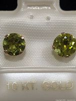 front view of both peridot stud earrings in packaging marked 10 KT. GOLD