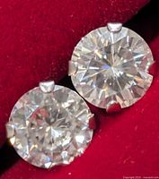 Close-up of both moissanite studs in case showing clarity and four-prong settings