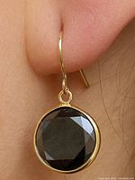 earring worn on ear showing size, yellow gold bezel and hook, black diamond
