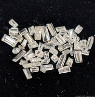 pile of small rectangular and round loose diamonds on black background