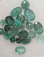 Close view of faceted emeralds loose on white pad
