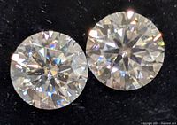 Close-up of two round brilliant cut moissanite stones showing facets and fire