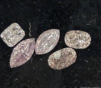 Five loose pink diamonds displayed on black background