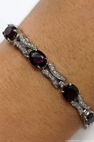 Bracelet worn on wrist showing garnet oval stones and CZ links