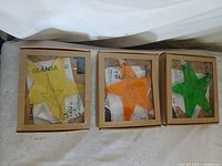 Three boxed Ikea Glansa wall stars yellow, orange, green