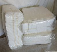 Three plastic-wrapped bundles of white diapers stacked