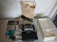 Camera, flash unit, box, Styrofoam, instruction card and dark slide laid out