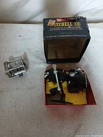 Garcia Mitchell 330 reel in box alongside metal casting reel