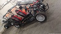 Side view of buggy showing frame, seats, front alloy wheel, rear steel wheel
