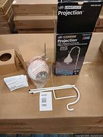 Box, projector head wrapped, pole sections, ground spike, hook arm, manual visible