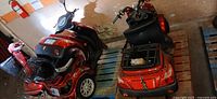 Two red electric three-wheel scooters on pallets, one mostly intact, one disassembled