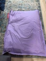 Full view of purple Fatboy beanbag on rug