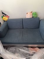 Front view of blue IKEA loveseat with plush toys on backrest