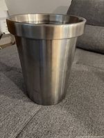 Front view of stainless steel trash can on sofa