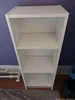 Front view of one white bookcase showing three shelves