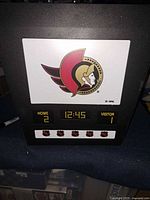 Front view showing Senators logo, digital windows and five puck logos