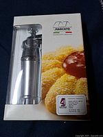 Front view of boxed Marcato biscuit maker showing tool and packaging