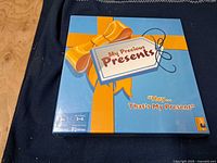 Front of sealed My Precious Presents board game box showing title, ribbon graphic, player count, teach time