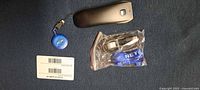 Scanner, badge reel, barcode card, bagged cable and strap on blue surface