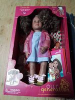 Front view of sealed Our Generation Denelle doll box showing doll, outfit, shoes and storybook