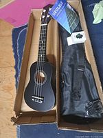 Ukulele in box with gig bag and tuner box visible