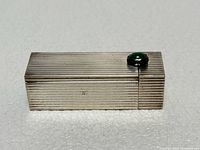 Closed ribbed silver lipstick case with green cabochon button