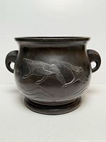 Front view of bronze jardiniere showing bird motif and handles