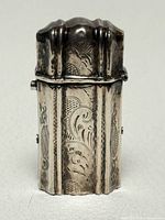 Front view of closed sterling match safe showing engraved design and patina