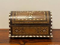 Front view of domed wooden jewelry box with inlay patterns