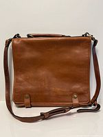 Front view of brown leather messenger bag with flap and shoulder strap