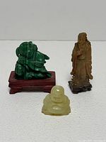 Group shot of three carved stone figurines with stands