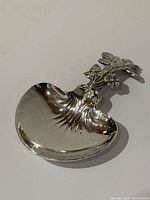 Front view of silver plated tastevin showing decorative handle and fluted bowl