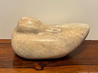 Side view of stone duck sculpture on wooden surface