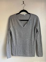 Full view of grey V-neck long-sleeve sweater on hanger