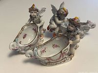 All three Dresden porcelain cherub sleigh nut dishes grouped