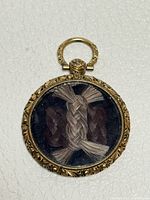 Front view of round gold-filled locket with braided hair visible