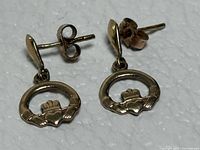 Front view of both earrings showing Claddagh design and stud posts with butterfly backs