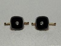 Front view of both cufflinks showing onyx faces and diamonds