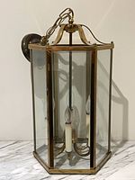 Full view of hexagonal brass and glass pendant lantern showing six candle sockets and glass panels