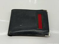 Front view of black leather Gucci wallet showing red/green web stripe and metal corner protectors