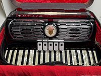 Front view of Titano accordion inside red-lined case showing keyboard, grill and register switches