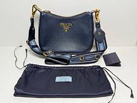 Front view of bag with strap, dust bag, papers