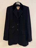 Front view of black wool Hermès coat on hanger