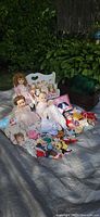 Group of dolls, furniture, clothing and bedding displayed outdoors