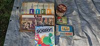 All six games displayed on tarp: Life, Clue, Sorry!, Mille Bornes, Password, Brain Teasers tin