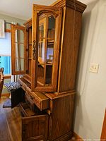 Side view showing full height of cabinet with upper glass doors open and lower drawers/doors closed