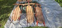 Three wooden sleds side by side on tarp outdoors